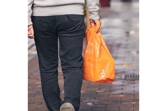 Person walking down the street holding a plastic bag in hand.